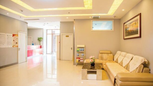 A hotel lobby with a reception desk, a sofa, a coffee table, and a framed picture on the wall. - Elan Hotel (Yantai Muping Bus Station) (Yantai)