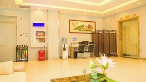 A hotel lobby with a reception desk, seating area, and a large framed artwork on the wall. - Elan Hotel (Yantai Muping Bus Station) (Yantai)
