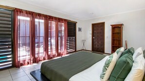 A bedroom with a large bed, curtains, a standing lamp, and a door. - Banyak Villa (Horseshoe Bay)
