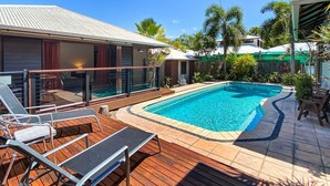 A swimming pool with lounge chairs, a covered deck, and a house with a metal roof. - Banyak Villa (Horseshoe Bay)