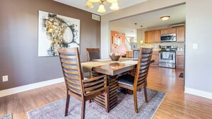 A dining area with a wooden table and chairs, a chandelier, and a large abstract painting on the wall. - Charming Kalamazoo Home w/ Yard: 1 Mi to Downtown! (Kalamazoo)