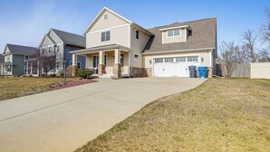 A two-story house with a front porch, garage, and a well-maintained lawn. - Charming Kalamazoo Home w/ Yard: 1 Mi to Downtown! (Kalamazoo)