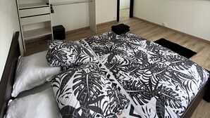 Ein Schlafzimmer mit Bett, Kleiderschrank, Flachbildfernseher und Ausgang zur Außenwelt.