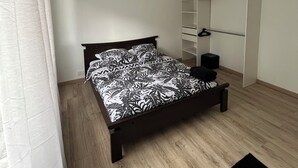 Ein Schlafzimmer mit einem Bett, einem Kleiderschrank, einem kleinen Hocker und einer Wanduhr.