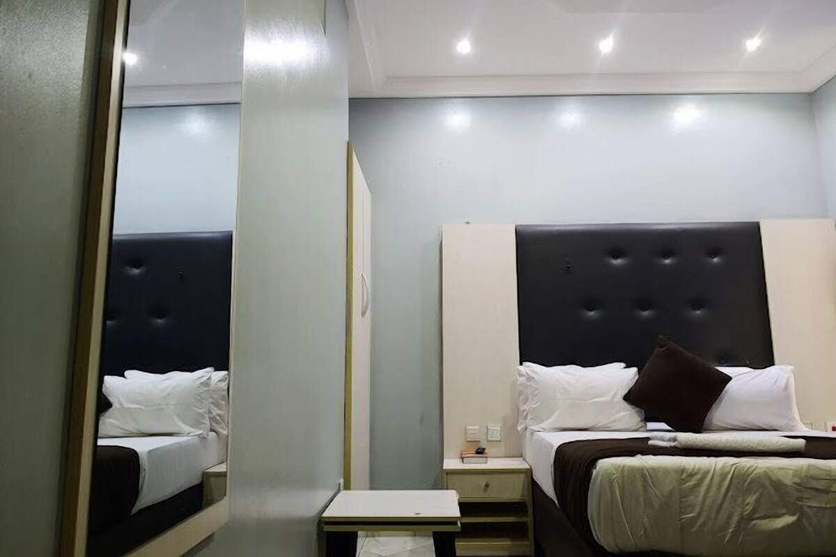Una habitación de hotel con cama, mesita de noche y espejo.