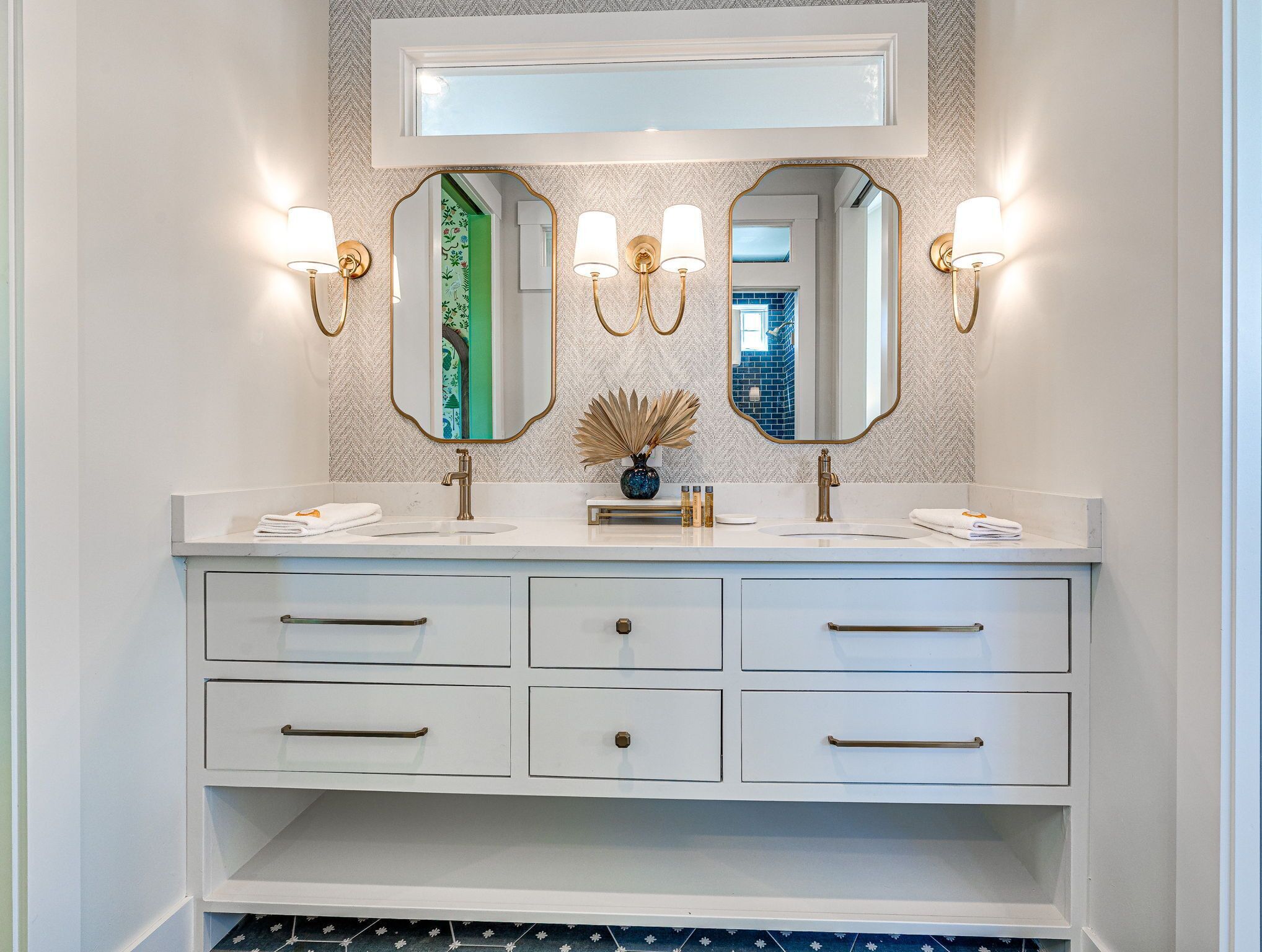 A bathroom vanity with two mirrors, wall sconces, and a sink.