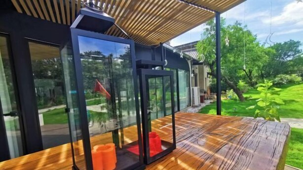 A modern outdoor seating area with glass enclosures and a wooden deck. - Suzhou Sanshan Island Zaidong Farm Boutique Homestay (Suzhou)