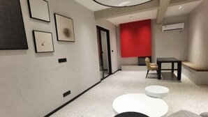 A modern interior with a hallway, framed artwork on the walls, a red accent wall, and a seating area with a table and chairs. - Suzhou Sanshan Island Zaidong Farm Boutique Homestay (Suzhou)