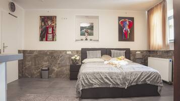 Un dormitorio moderno con una cama grande, paredes de mármol, un reloj y obras de arte.