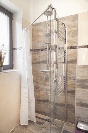 A modern shower with a glass enclosure, chrome fixtures, and a tiled wall with a marble-like pattern. - Amir Deluxe Motel (Schoenefeld)