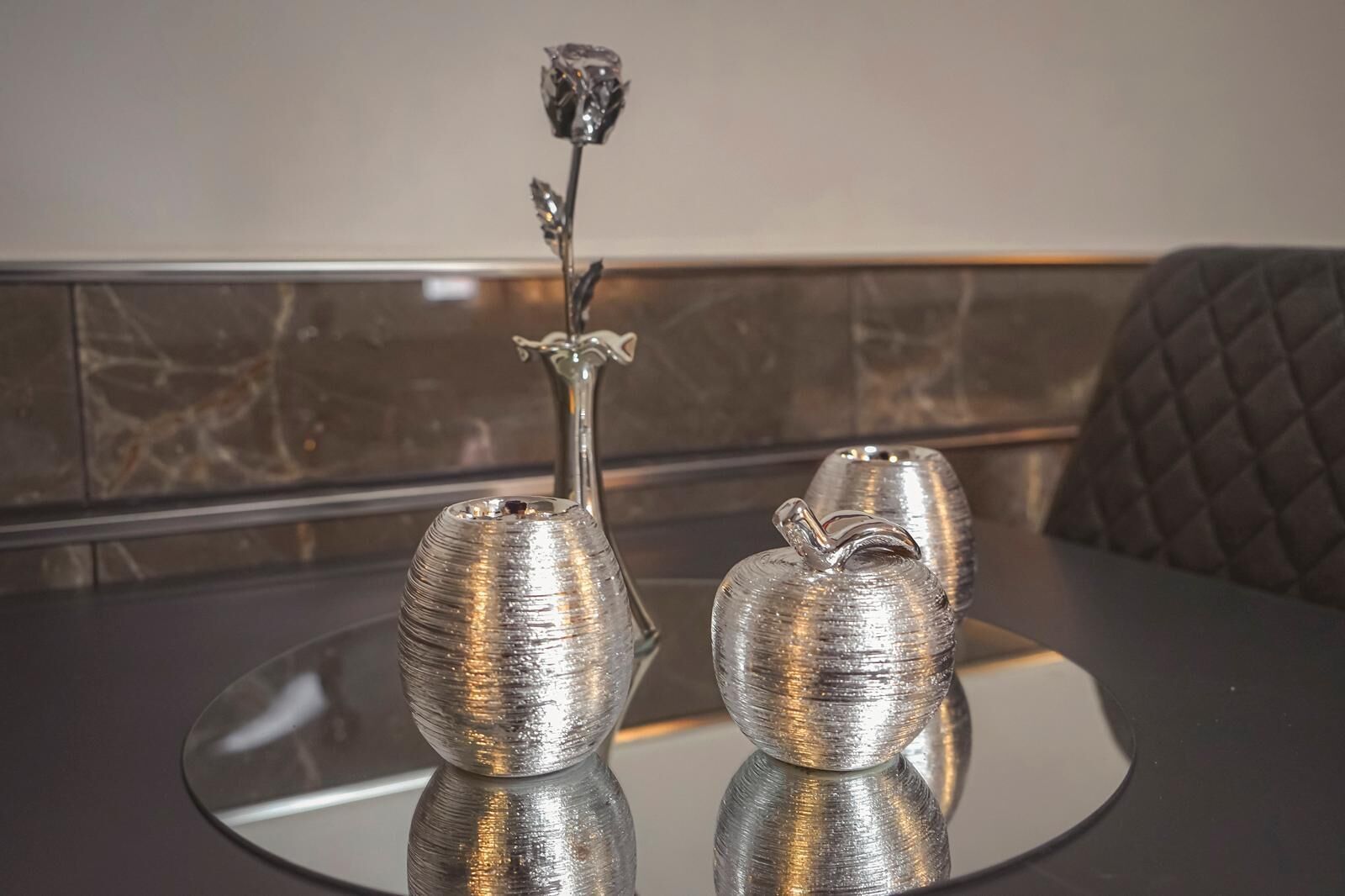 Two metallic vases on a reflective surface.