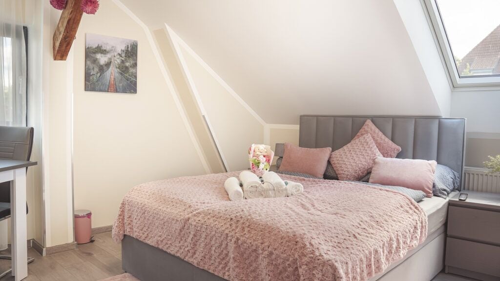 A bedroom with a bed, bedside table, and a window.