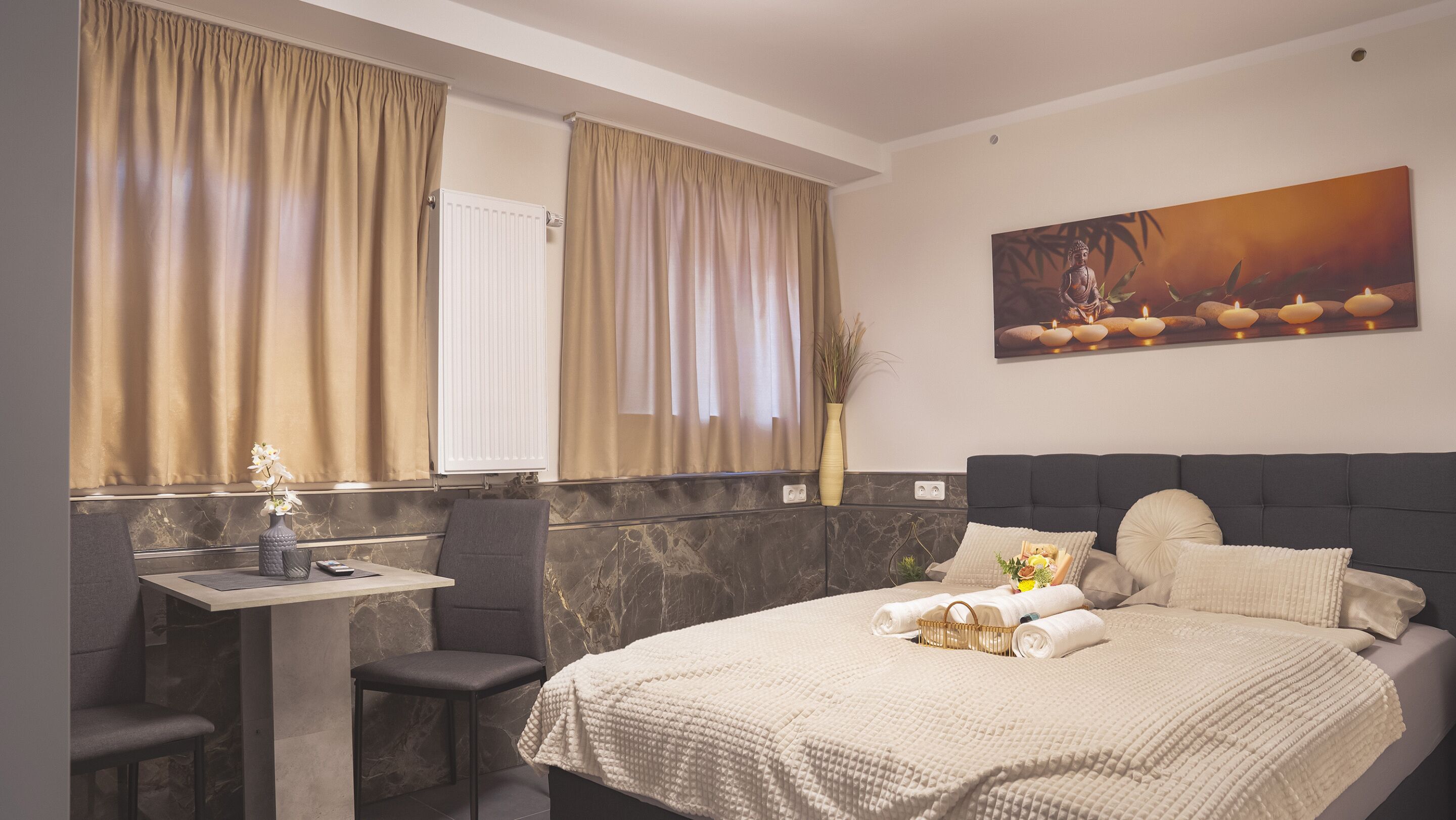 A bedroom with a bed, a bedside table, a chair, a window with curtains, and a painting on the wall.