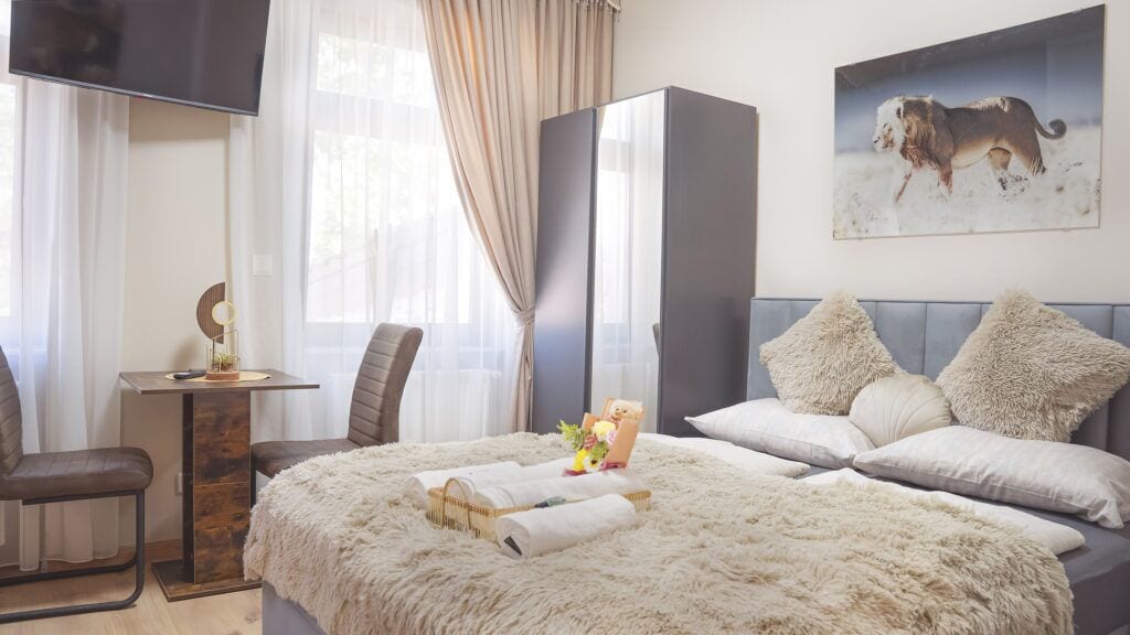 A hotel room with a bed, a desk, a chair, a wardrobe, and a painting on the wall.