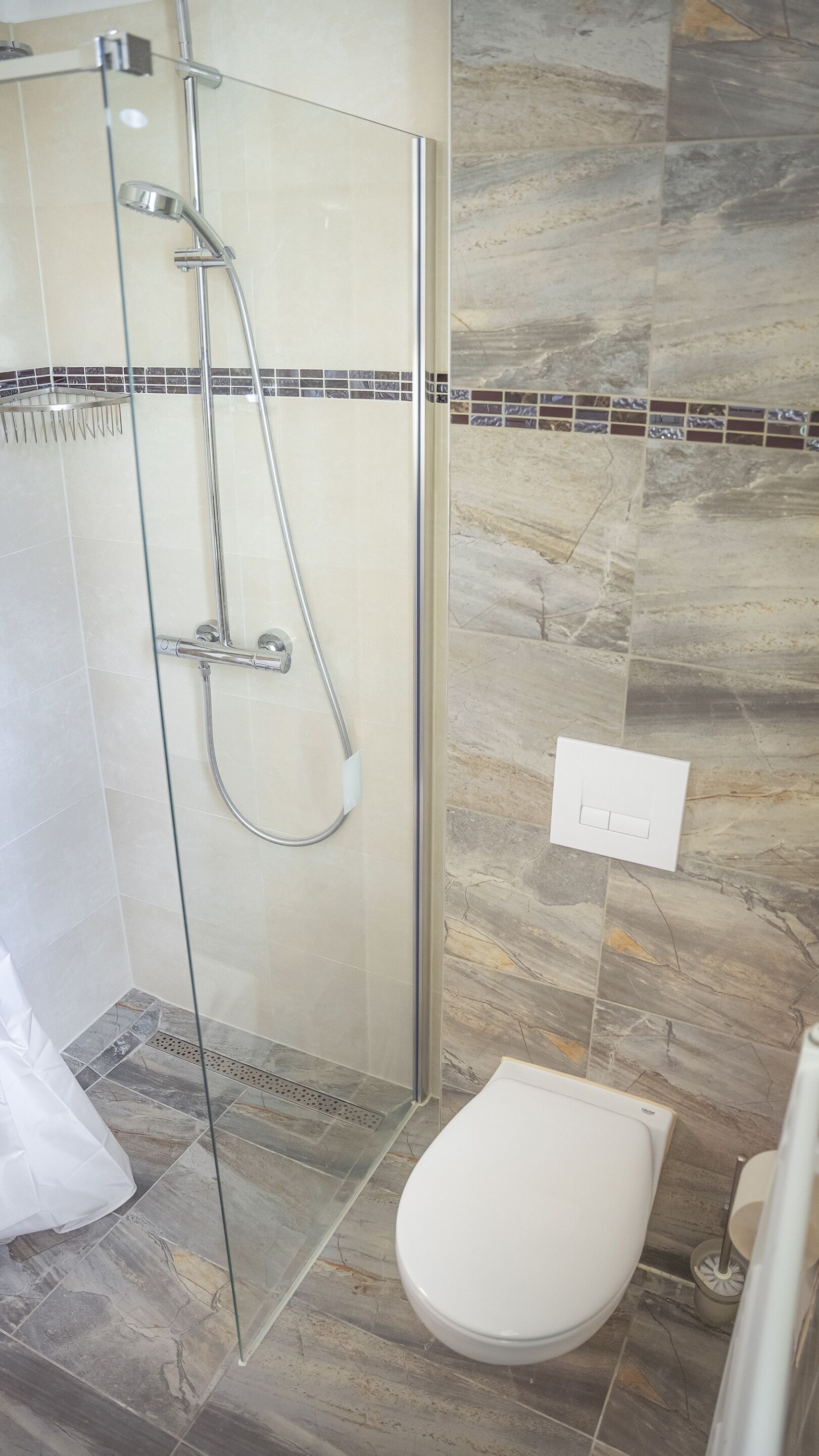 A modern bathroom with a glass-enclosed shower, a white toilet, and a marble-tiled floor.