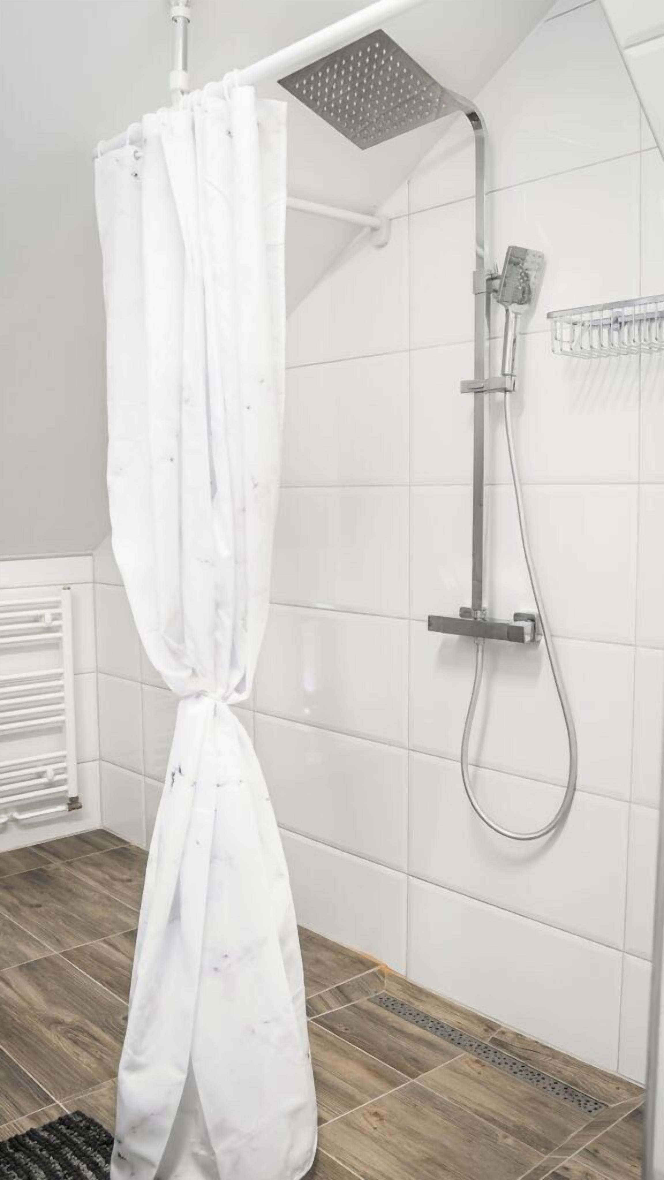 A shower area with a white showerhead, a handheld showerhead, and a shower caddy.