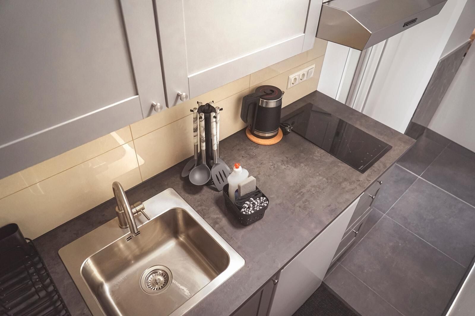 Uma cozinha moderna com uma pia de aço inoxidável, uma cafeteira e diversos utensílios de cozinha.