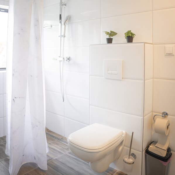 A modern bathroom with a toilet, shower, and two potted plants on the wall. - Amir Deluxe Motel (Schoenefeld)