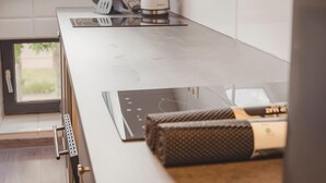 Een moderne keuken met een ingebouwde kookplaat, een waterkoker en een raam boven het aanrecht.
