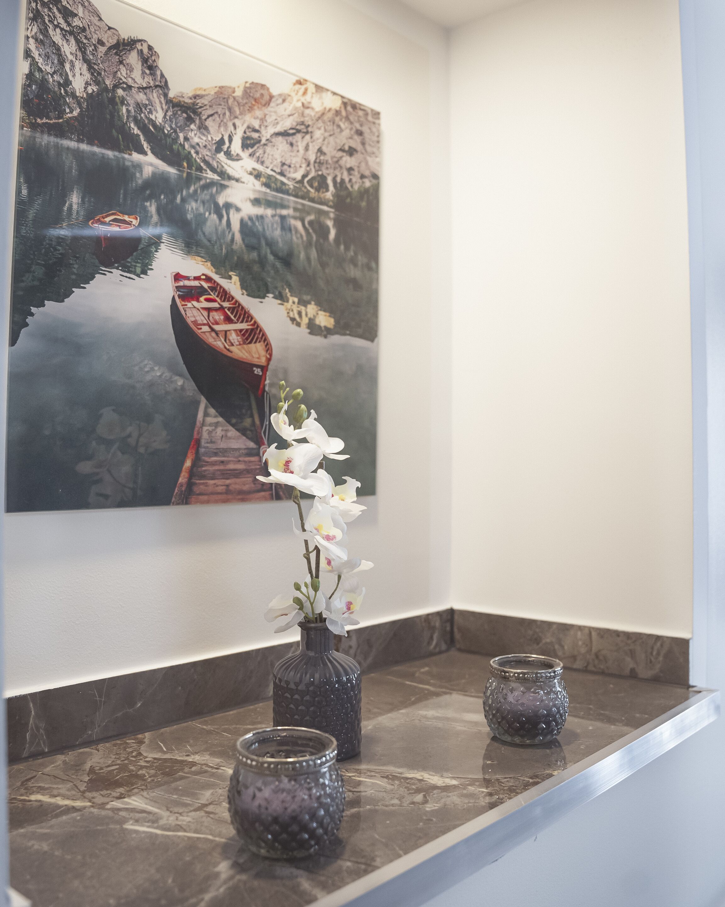 A marble-topped shelf with a vase of white flowers and two small decorative jars.