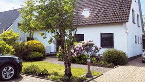 A two-story house with a tiled roof, a small front garden, and a paved driveway. - Apartment in Esens, Deutschland (Esens)