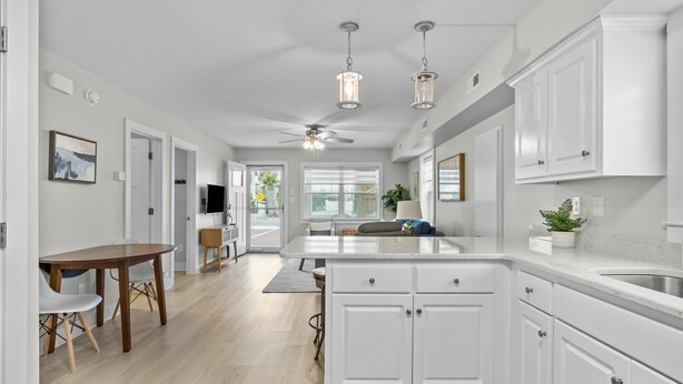 A modern kitchen with white cabinetry, a central island, and pendant lighting. - Walk on the Beach "Downtown" - your feet in the sand in 250 ft.  Pet friendly (Atlantic Beach)