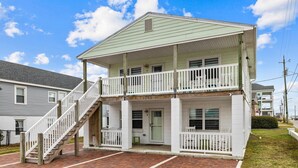 A two-story house with a front porch, a staircase, and a brick driveway. - Walk on the Beach "Downtown" - your feet in the sand in 250 ft.  Pet friendly (Atlantic Beach)