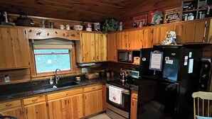 Una cocina con armarios de madera, un refrigerador negro, un microondas y una estufa.