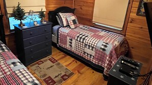 Un dormitorio acogedor con cama, cómoda y un pequeño escritorio con lámpara y adornos.