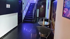A hallway with a staircase, a metal chair, and a door with a no-smoking sign. - Hale Manor Exquisite (Benin City)