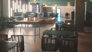 Een ruim restaurant met hoge tafels en stoelen, een podium voor optredens en sfeerverlichting.