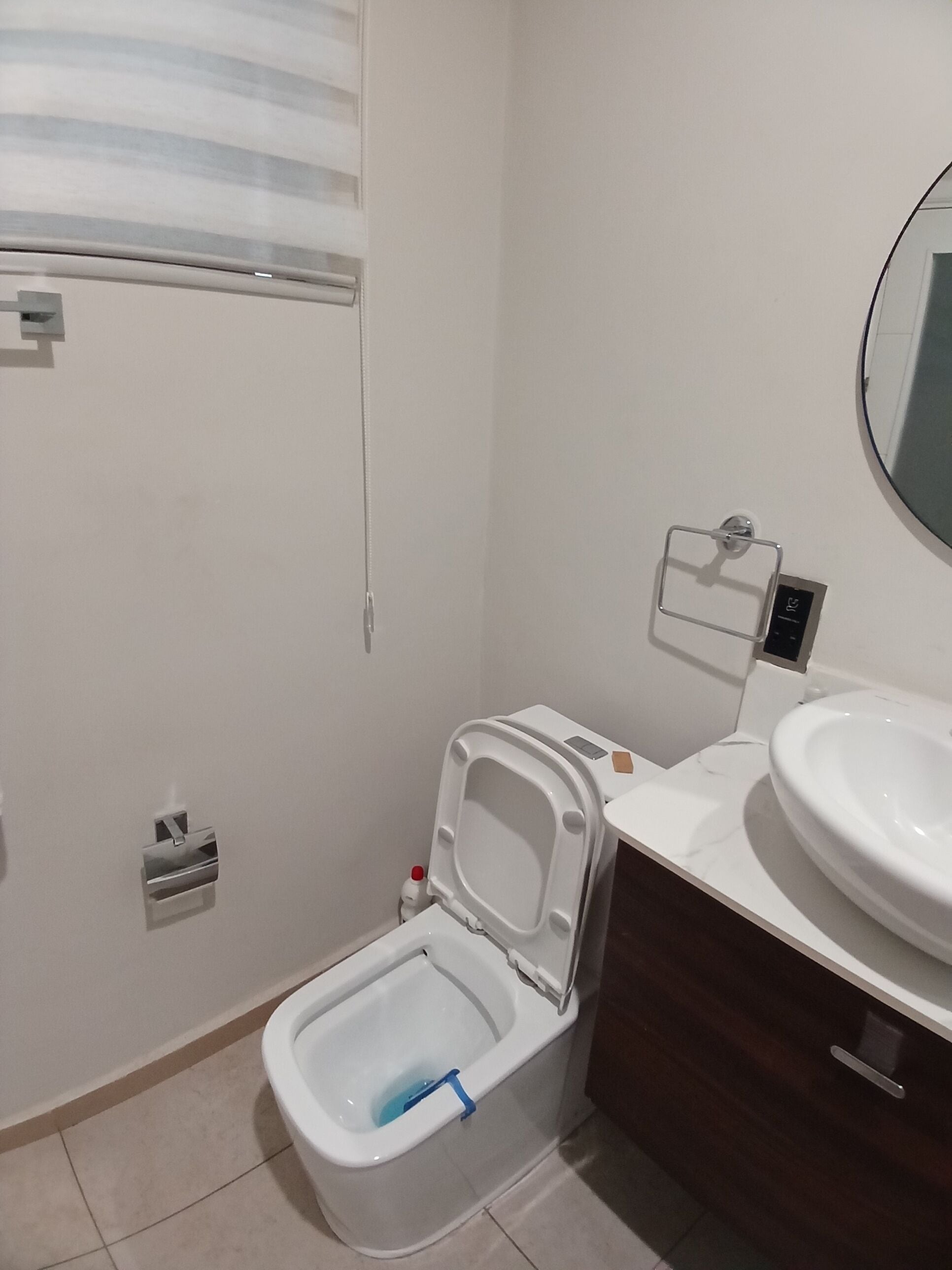 Un baño con inodoro, lavamanos y espejo.