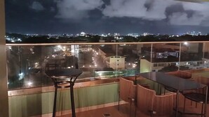 Een balkon met een glazen balustrade, een tafel en twee stoelen.