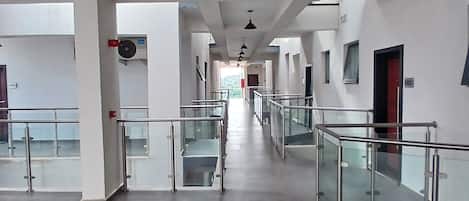 A spacious corridor with glass railings and a modern design, leading to multiple rooms.