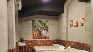 Ein Schlafzimmer mit zwei Betten, einem kleinen Schreibtisch und einem Wandgemälde.