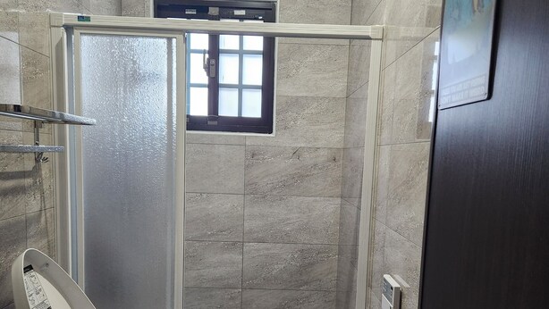 Une salle de bain moderne équipée de toilettes, d’une douche et d’une porte.