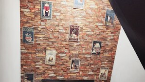 Ein Zimmer mit Backsteinwand, verziert mit verschiedenen Postern und einem Fenster.