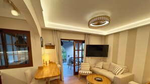 Un salon moderne avec une table à manger en bois, un canapé, une table basse et un téléviseur fixé au mur.