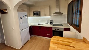 Une cuisine compacte équipée d’un four à micro-ondes encastré, d’une cuisinière et d’un évier.