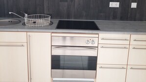 Cuina amb disseny modern, que destaca per un obrador d'acer inoxidable, una placa de cocció negra i un forn integrat.