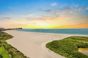 A coastal landscape with a wide sandy beach, a clear sky, and a sunset. - Penthouse Beachfront Condo | Pool/Fitness/Grills (Marco Island)