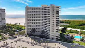 Ein Hochhaus-Hotel mit mehreren Balkonen, einem Schwimmbad und Blick auf Strand und Meer.