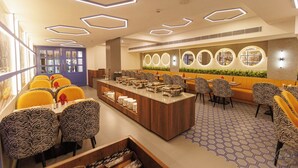 A modern restaurant with a central counter, zebra-patterned chairs, and a hexagonal ceiling design. - mannat residency by io hotels (Amritsar)