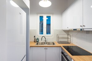 A modern kitchen with a double sink, a built-in oven, and a window with a view. - Alex’s 2-Bedroom Apartment in Athens (Greece - Athens)