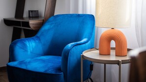 En blå lænestol ved siden af et rundt bord med en lampe.