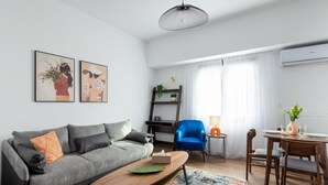 Ett modernt vardagsrum med en grå soffa, ett träbord som soffbord, en blå fåtölj och en matplats med ett bord och stolar.
