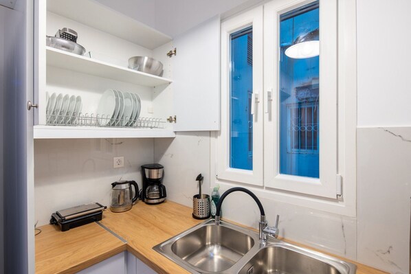 A modern kitchen with stainless steel appliances, a coffee maker, and a window with blue tint.