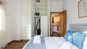 Et soveværelse med seng, garderobeskab, badeværelse synligt gennem en åben dør og en hængende lampe.