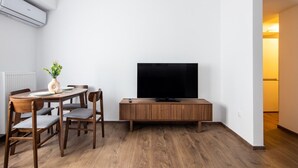 En kompakt opholdsstue med spisebord, stole, et fladskærms-tv og et træskab.