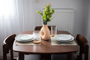 Une table à manger avec deux assiettes, un vase contenant des fleurs vertes et deux verres transparents.